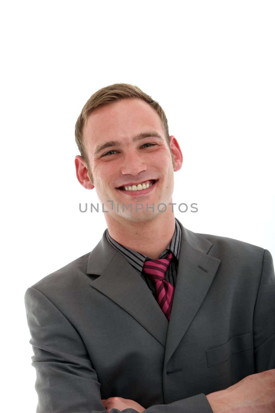 Smiling confident handsome young businessman standing with his arms folded isolated on white