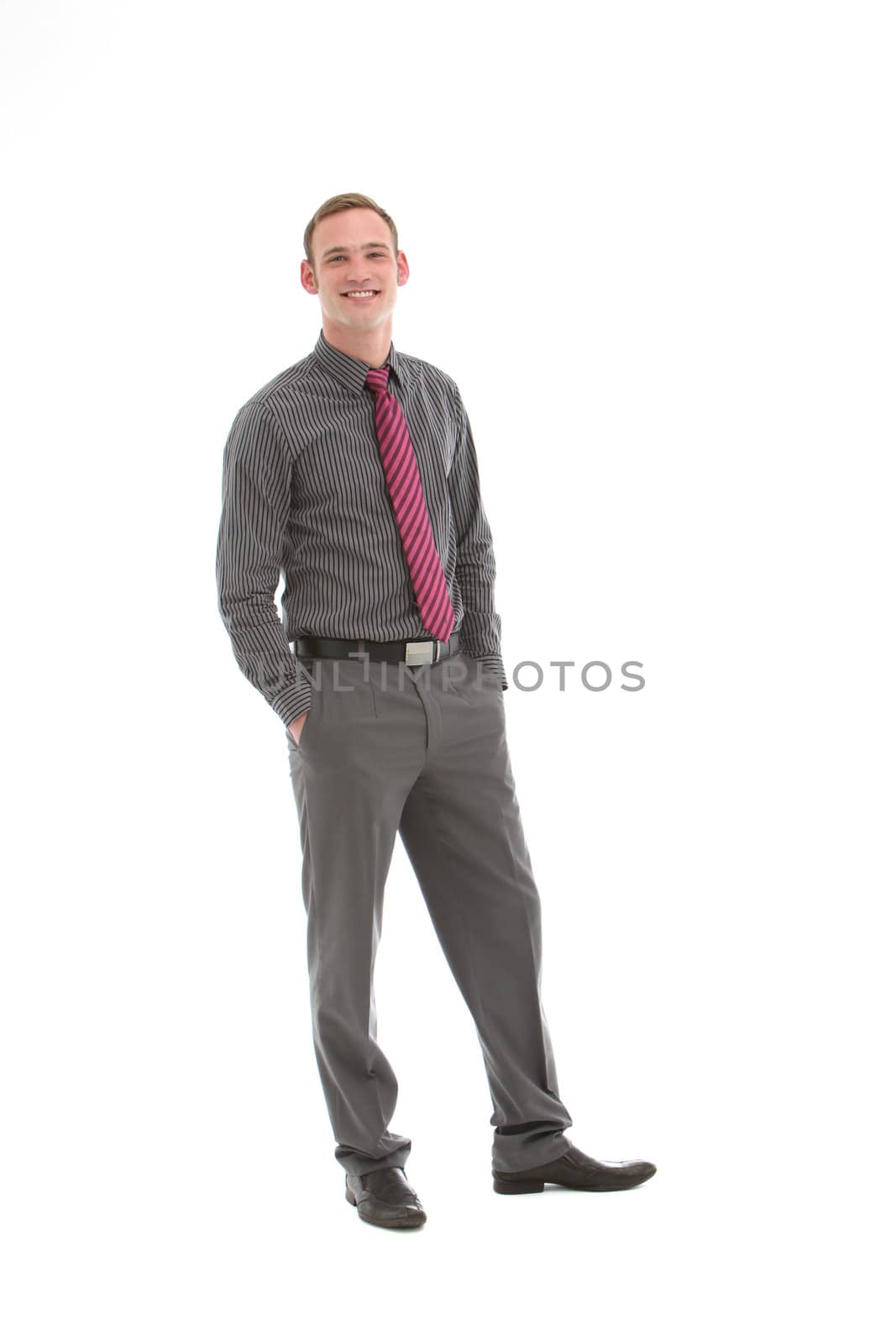Elegant stylish businessman in striped grey shirt and trousers with his hands casually in his pockets posing full length on white studio background