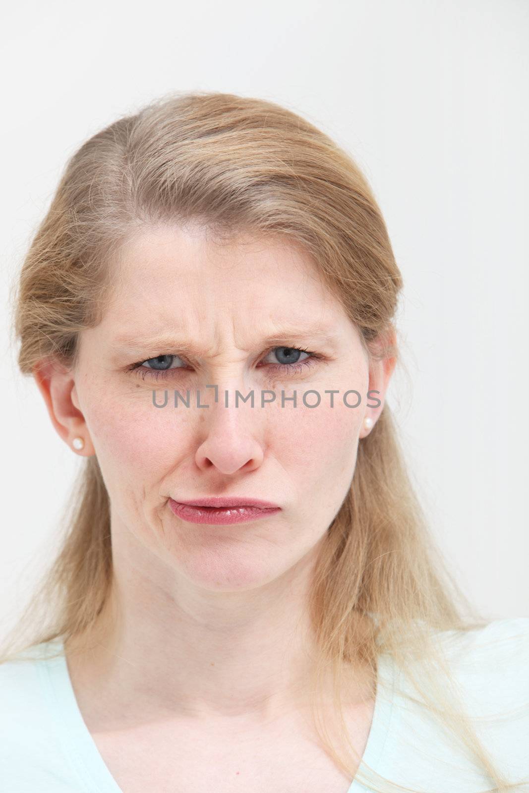 Facial portrait of an attractive young blonde woman with a frowning lopsided quizzical expression