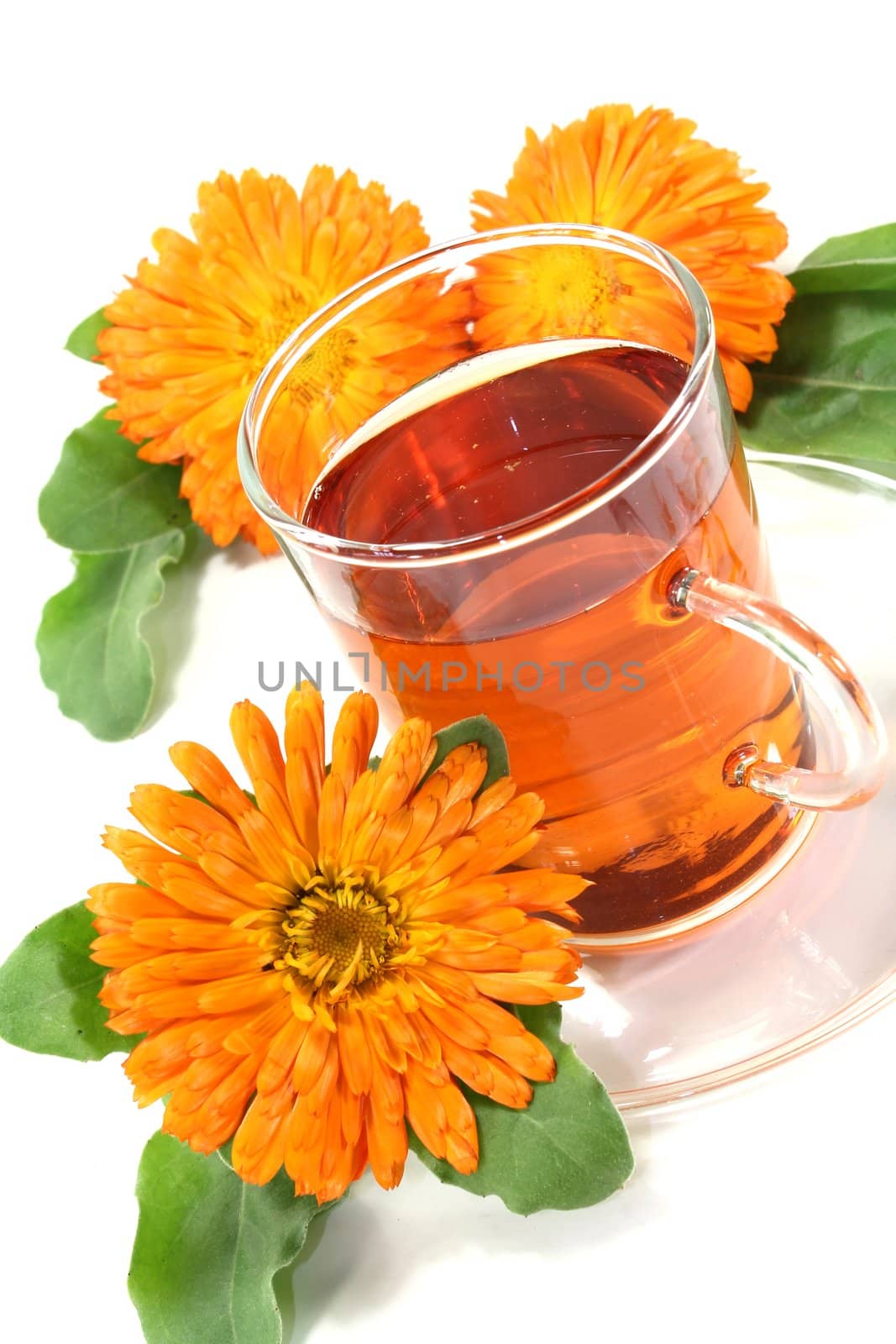 a glass of marigold tea and calendula flowers on a bright background