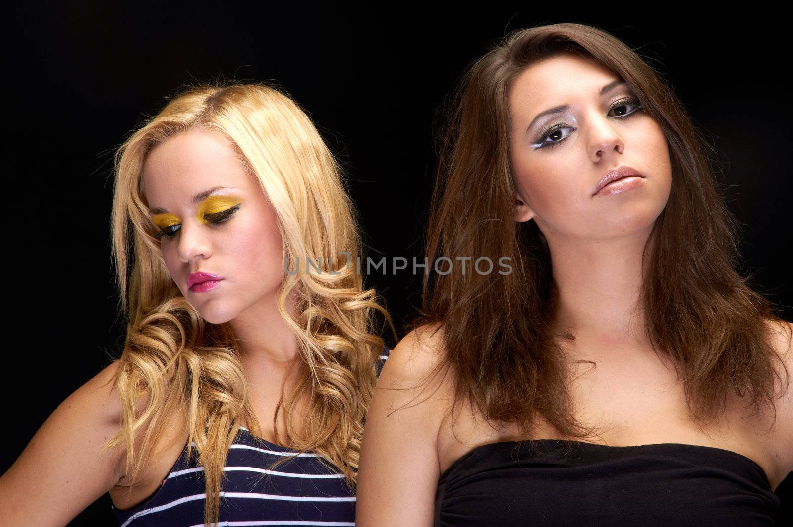 Closeup photo of two young girls in the studio against dark background