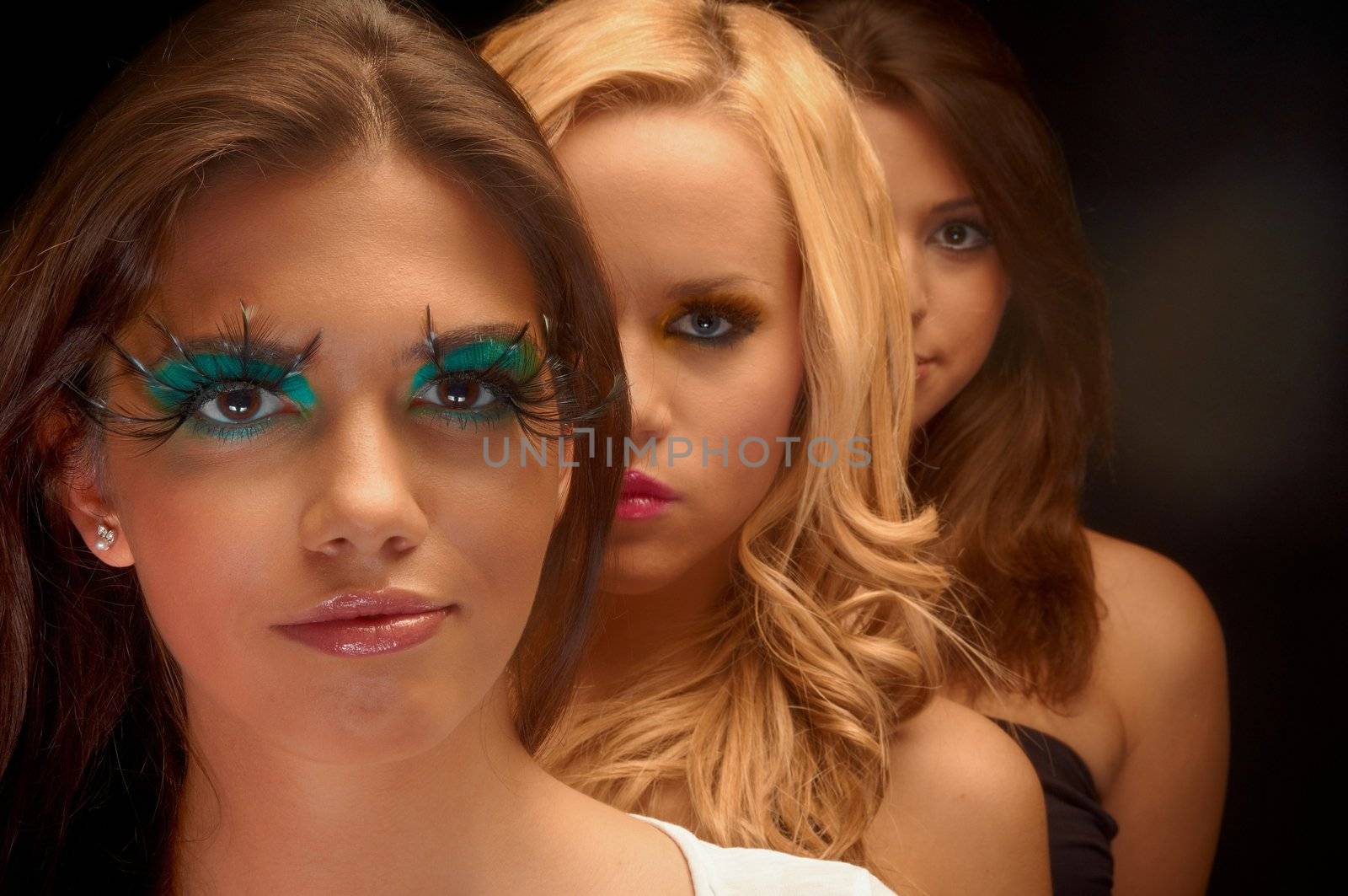 Some girls lined up in a studio with makeup