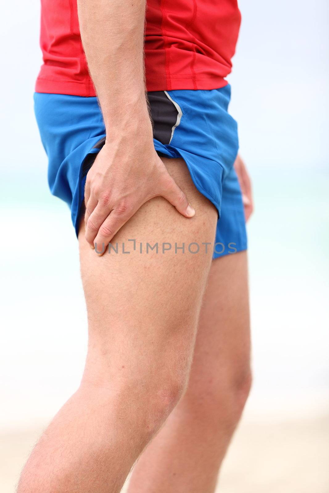 Muscle sports injury. Running muscle strain injury in thigh. Closeup of runner touching leg in muscle pain.