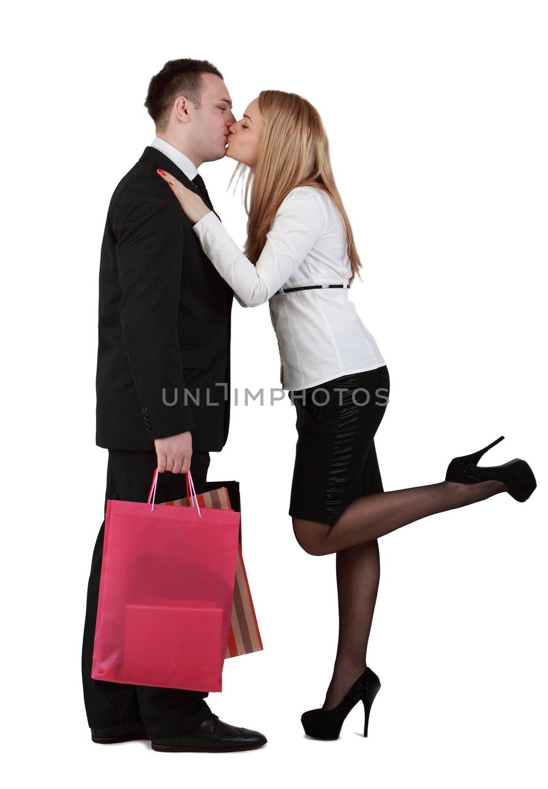 Young couple with shopping bags kissing against a white background.