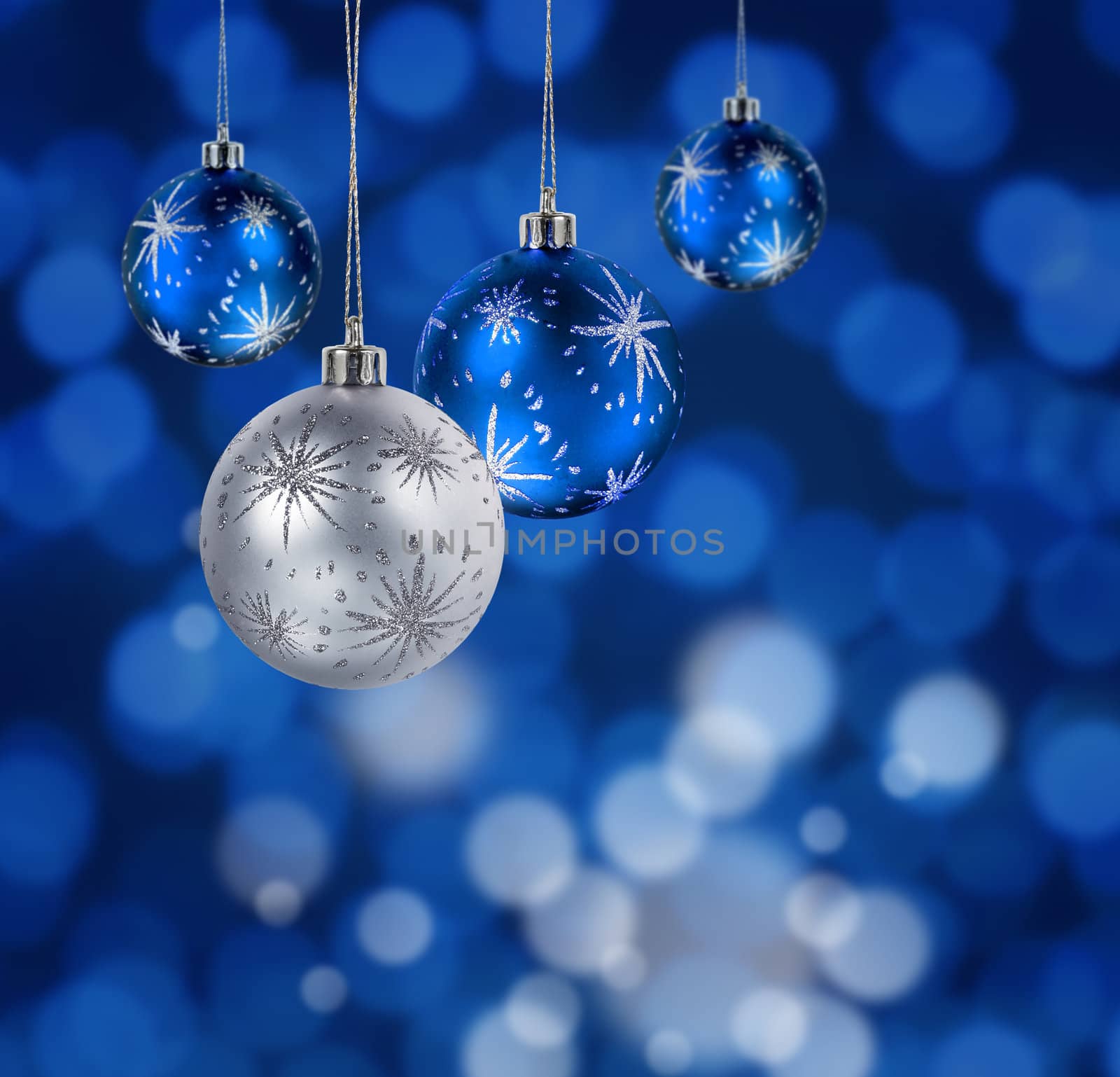 Blue and silver Christmas balls hanging against blue light spots background