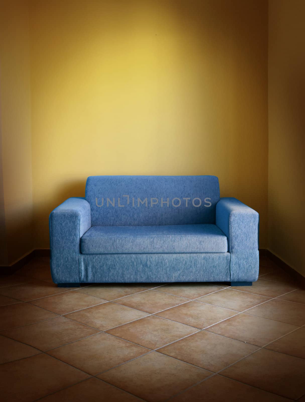 Blue vintage sofa on terracotta tiled floor in yellow room