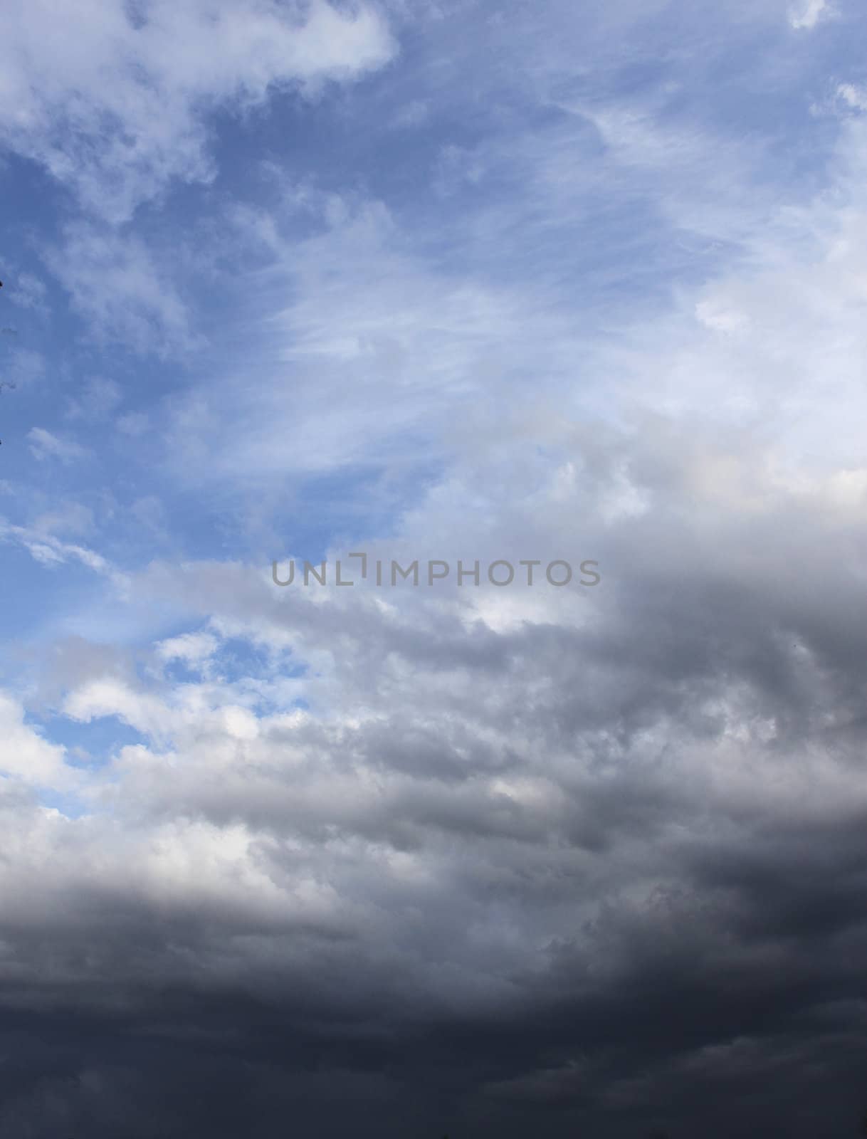 Dark rain clouds gathering on blue sky background