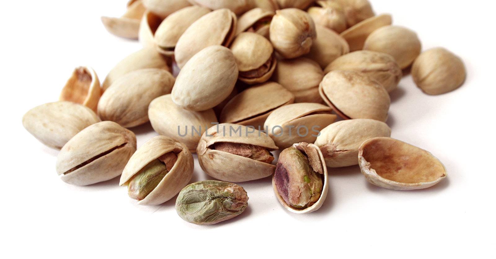 Dried and salted pistachio nuts on white background