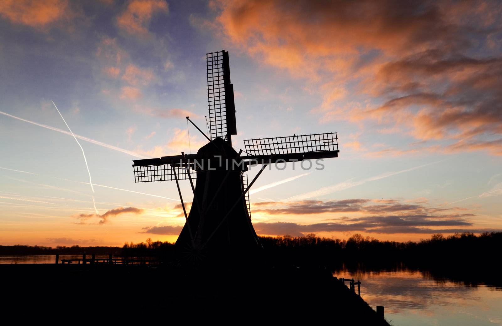 silhouette of Dutch windmill over sky during sunset