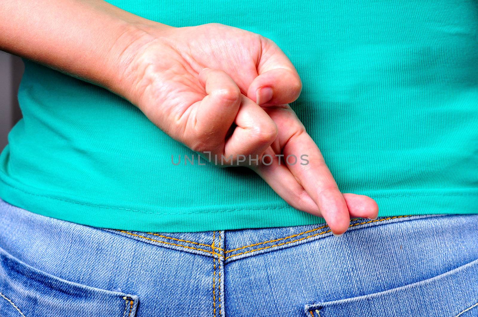 Close up of crossed fingers behind a woman's back