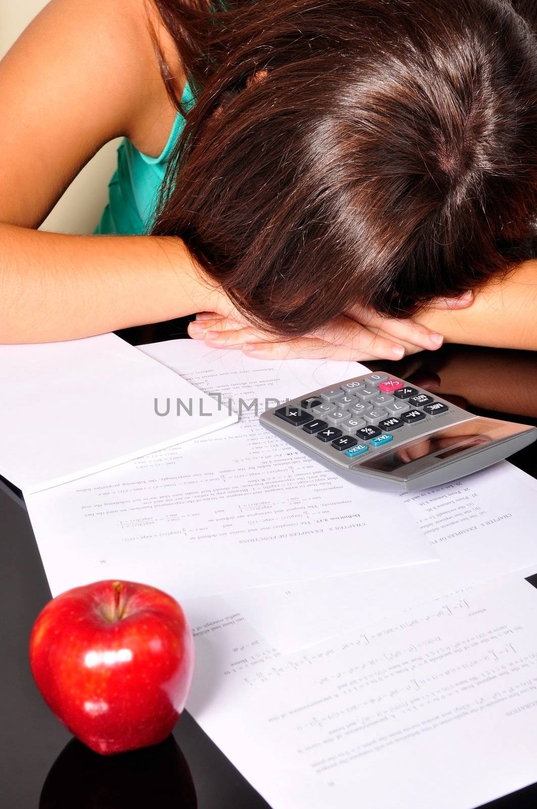 Young woman, tired of studying, sleeping over maths exercises