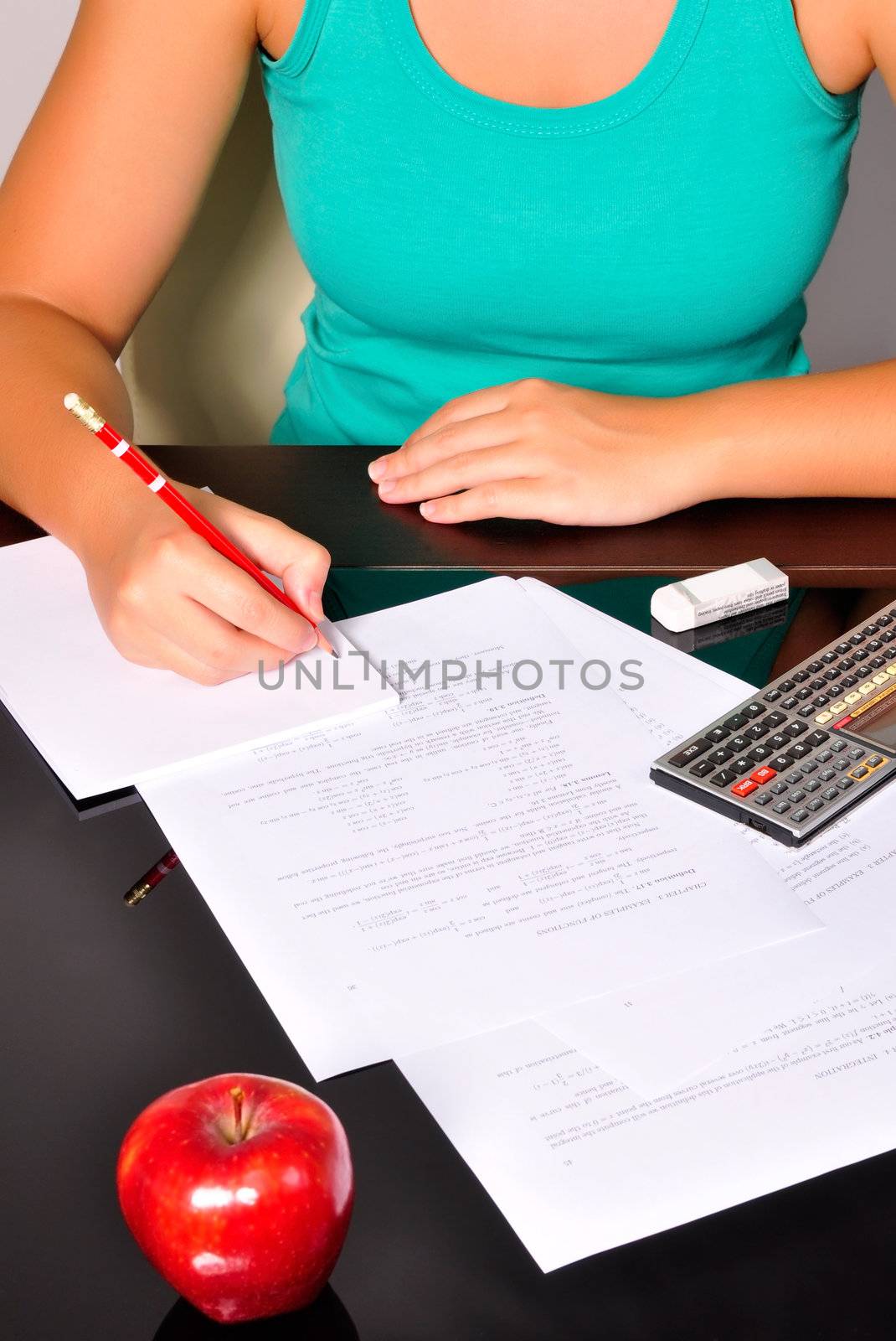 Student doing maths exercices with a calculator and a red pencil.
