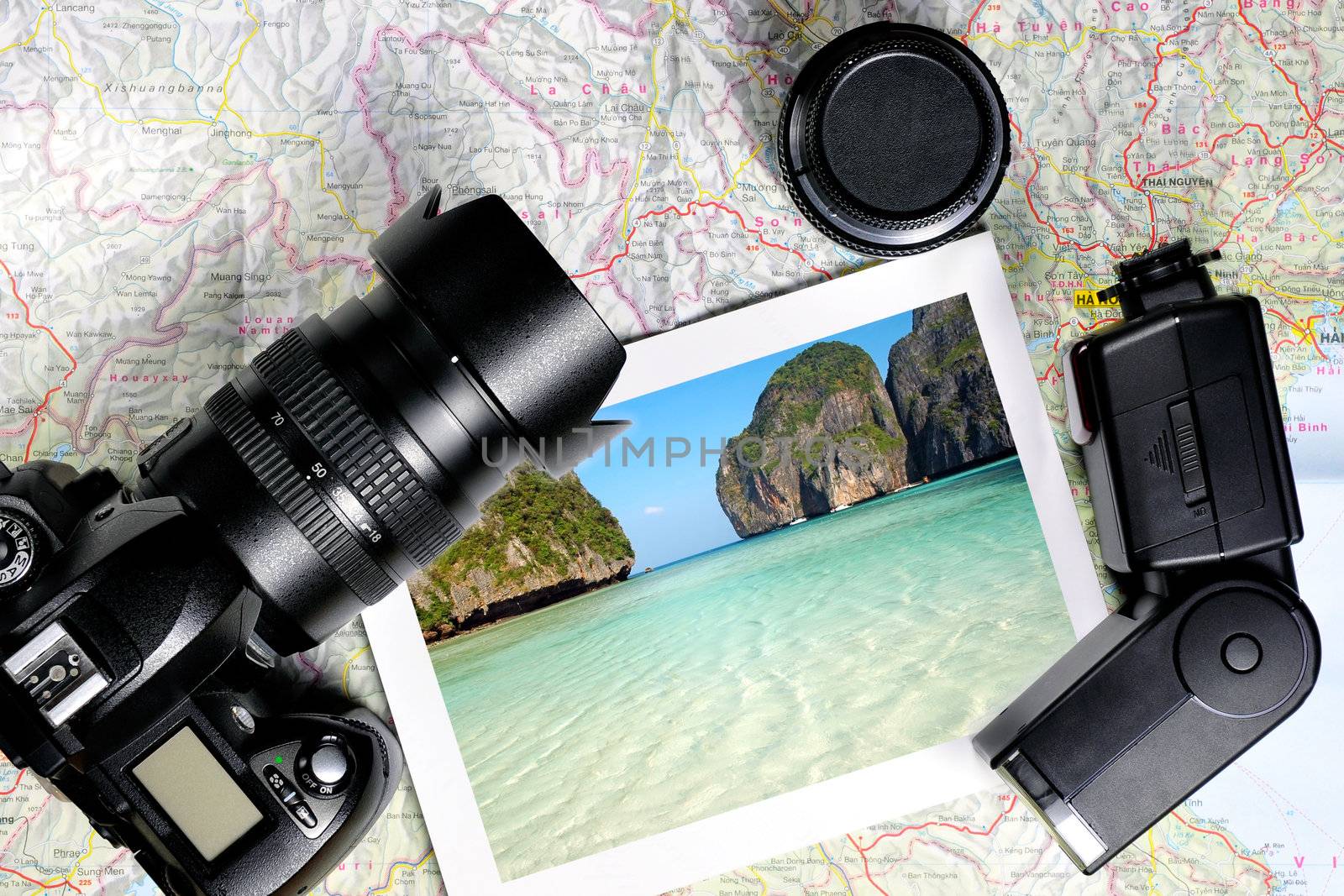 Digital camera, lens, flash and a photo layed on top of a map of Thailand
