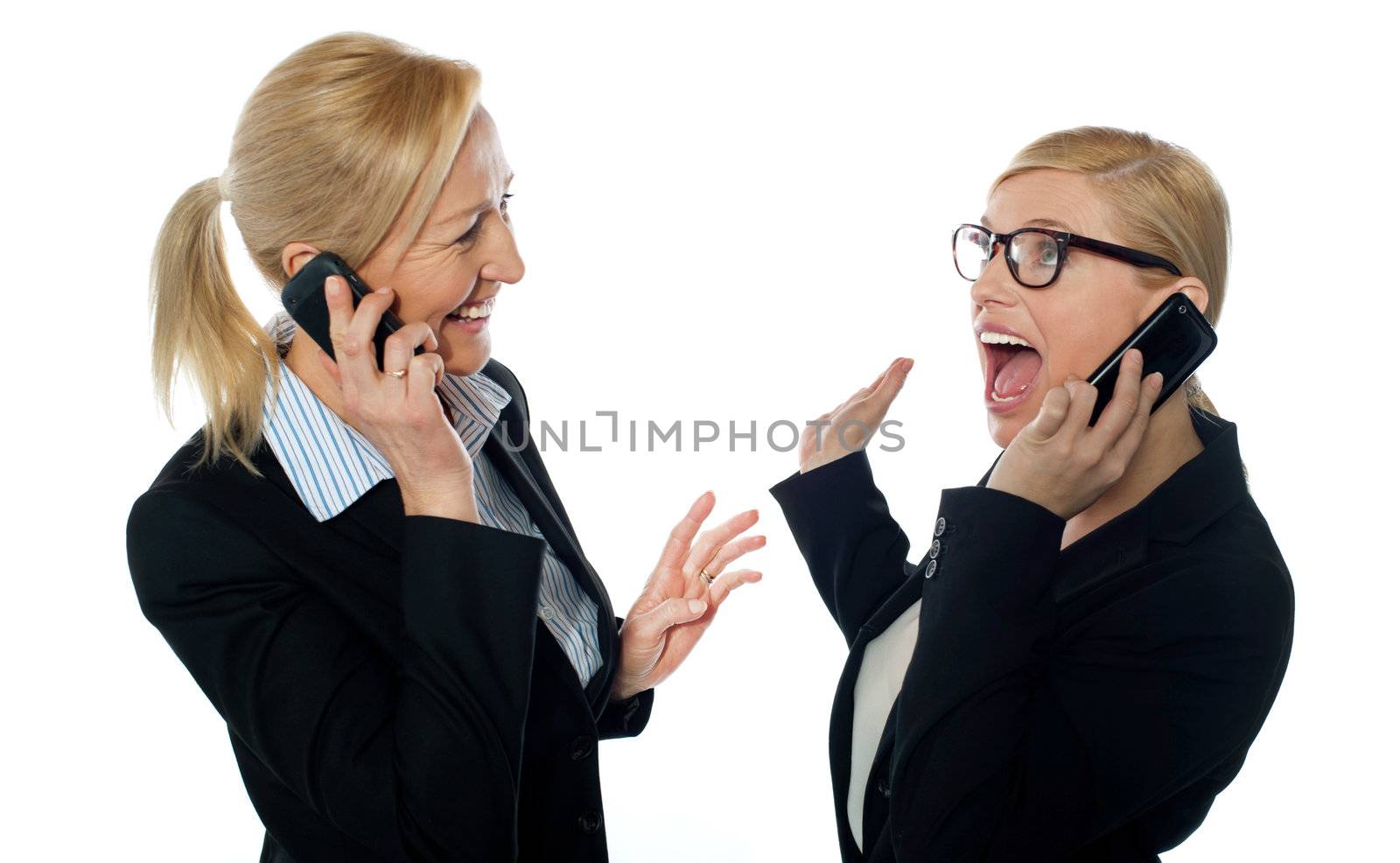 Happy businesswomen communicating on cellphone looking each other