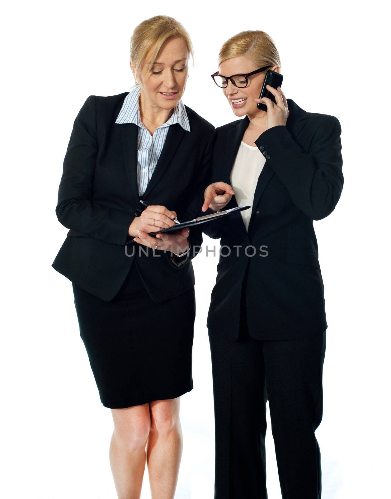Two females looking at progress report and discussing. One of them also communicating on mobile phone