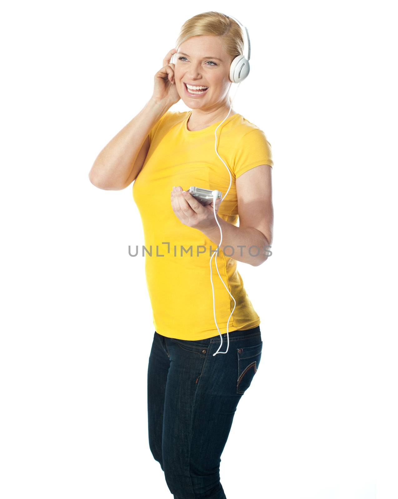 Pretty woman holding music player with headphones attached. Enjoying music