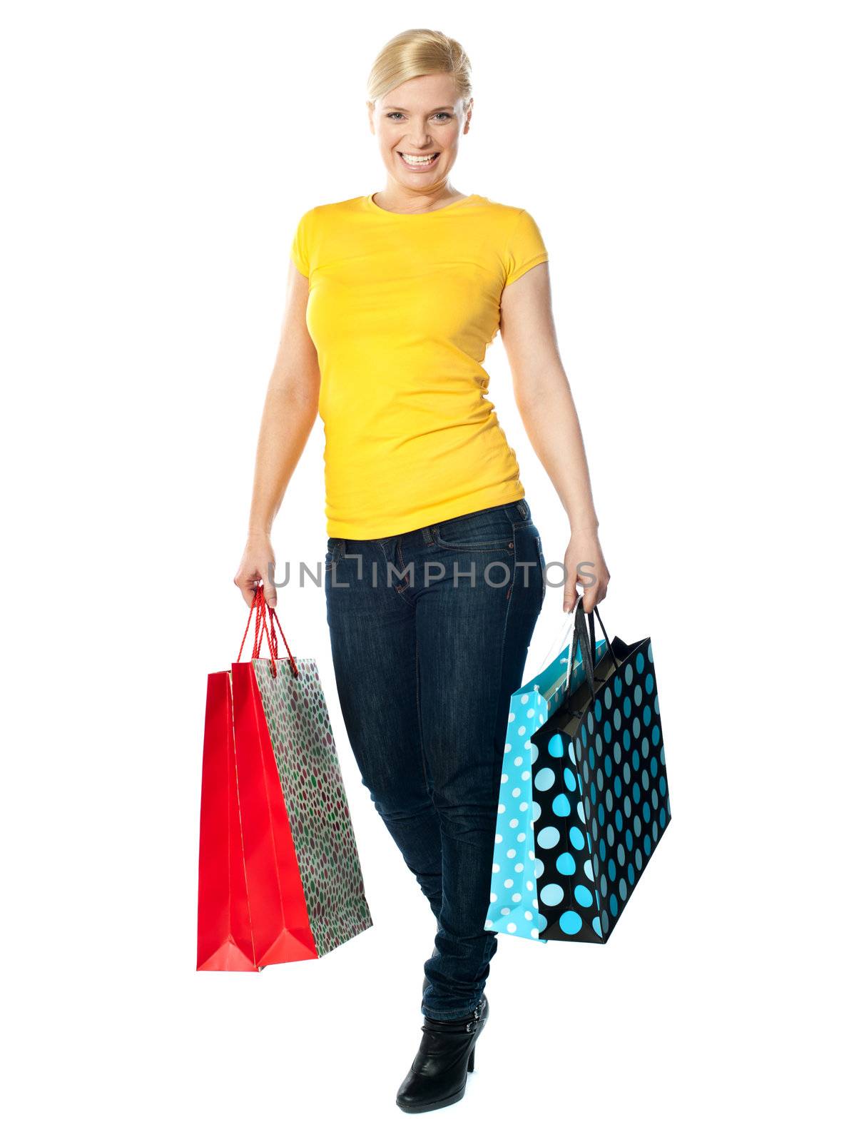 Attractive girl carrying colourful shopping bags, walking pose