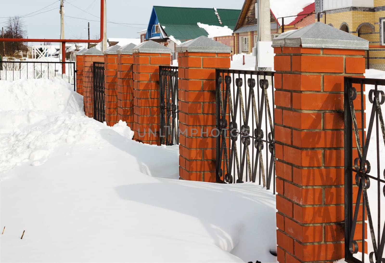 Red fence covered with snow in winter