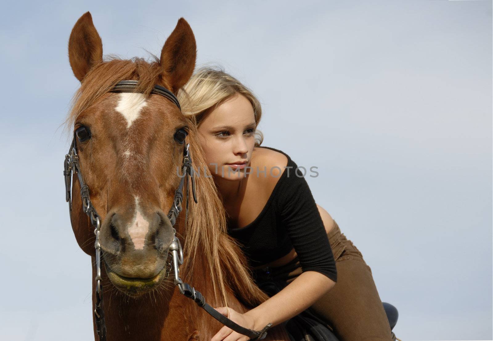 blond teenager and her brown horse in blue sky