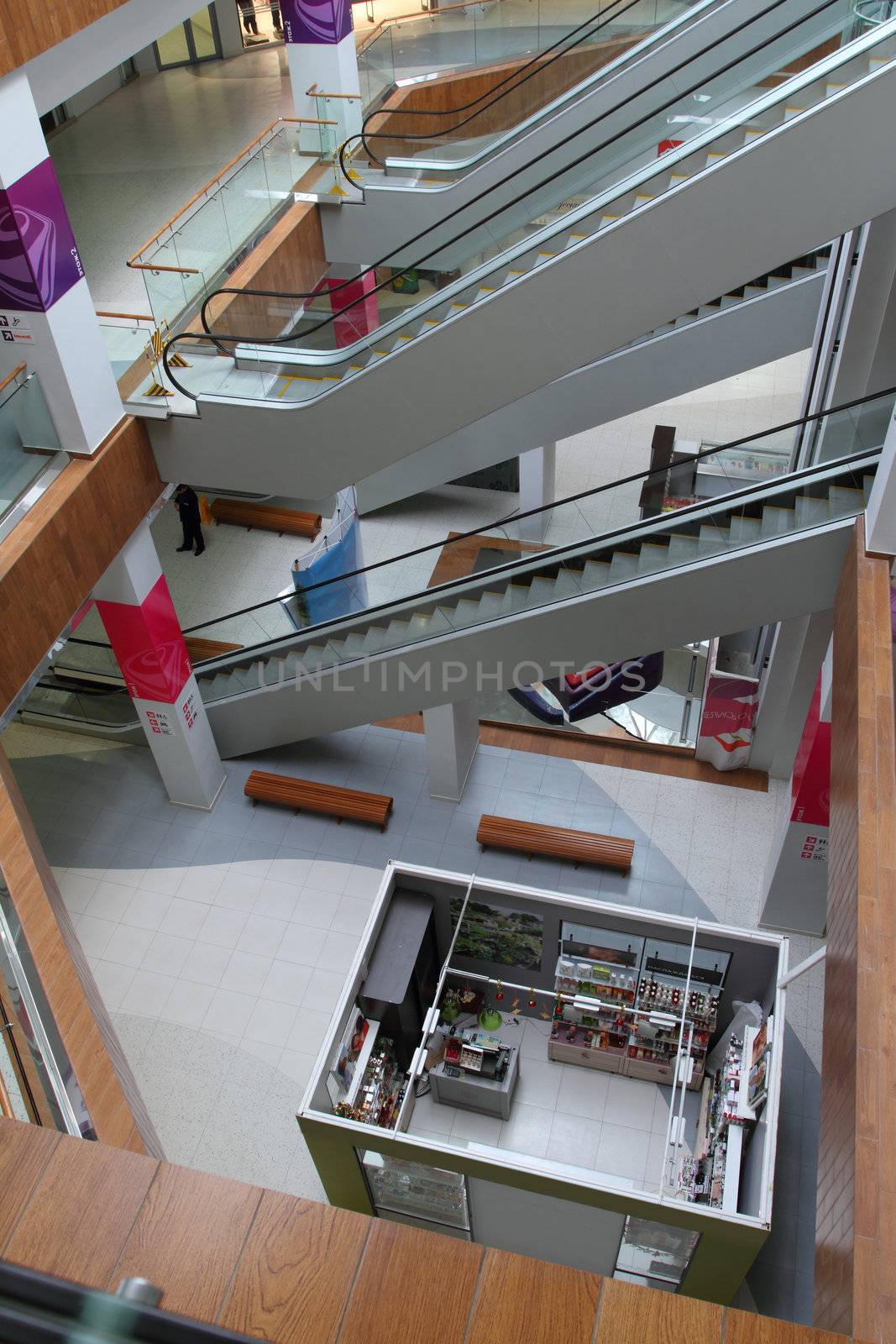 Hall with columns and escalators in huge shopping center. View of floors and ladders from above