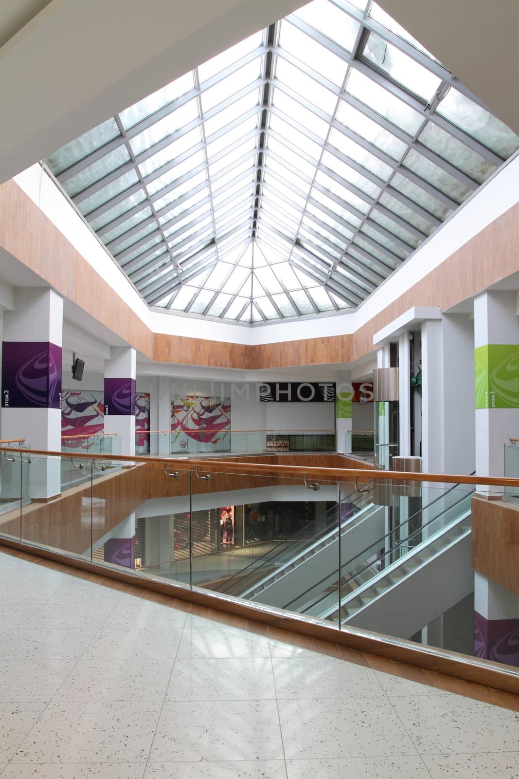 Hall with columns and escalators in huge shopping center. A view of the glazed ceiling