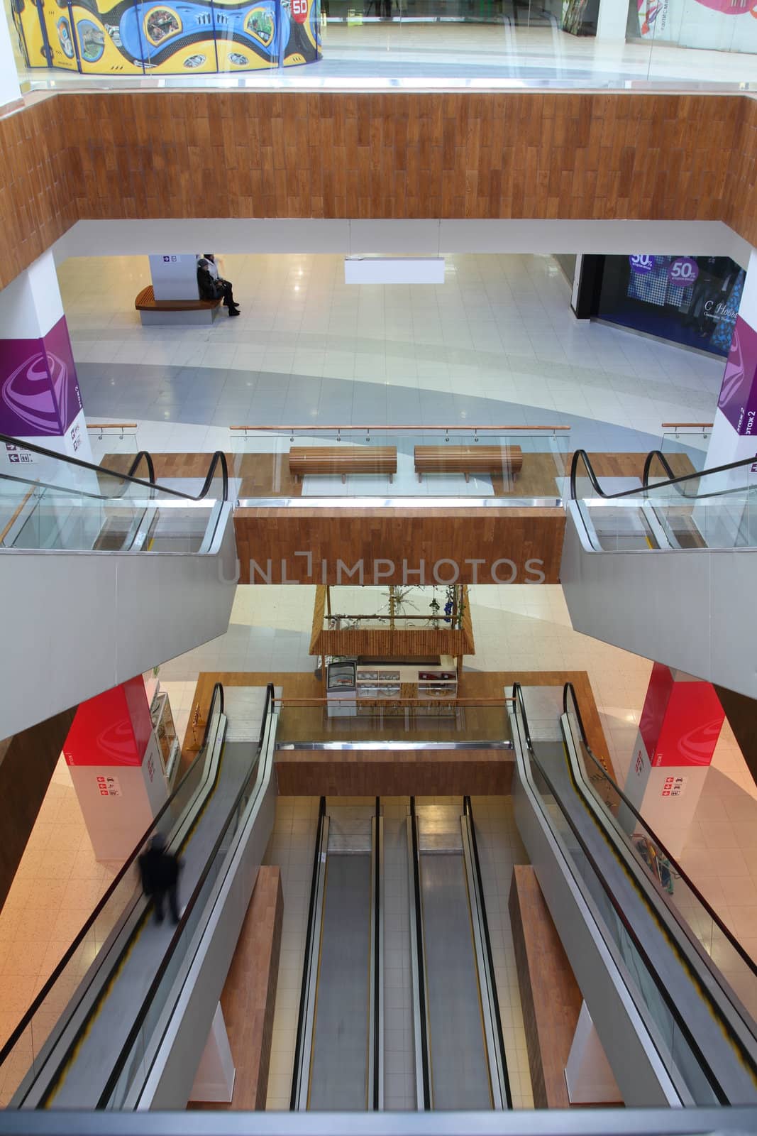 Hall with columns and escalators in huge shopping center. View of escalators from top to down