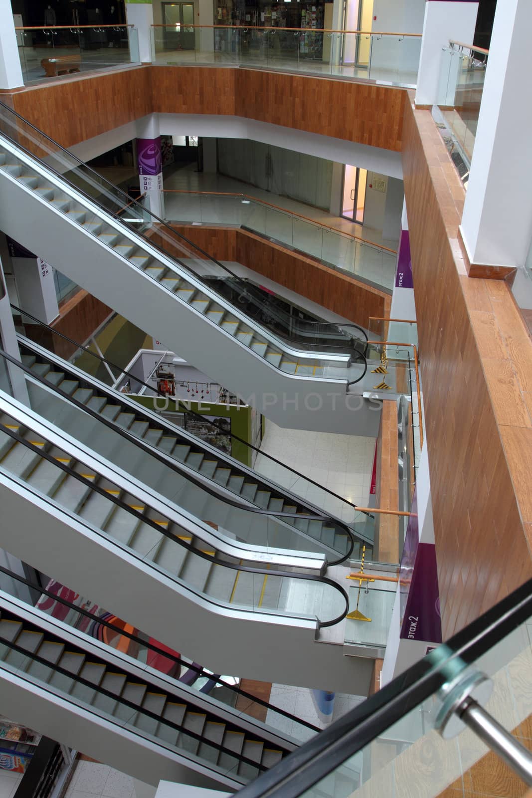 Hall with columns and escalators in huge shopping center. A view from the top floor on escalators