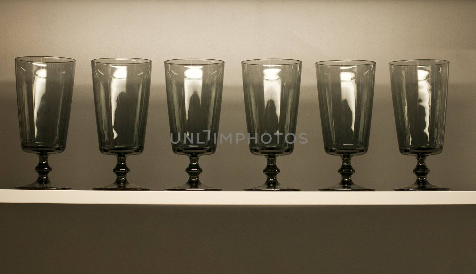 six empty glasses on a white shelf