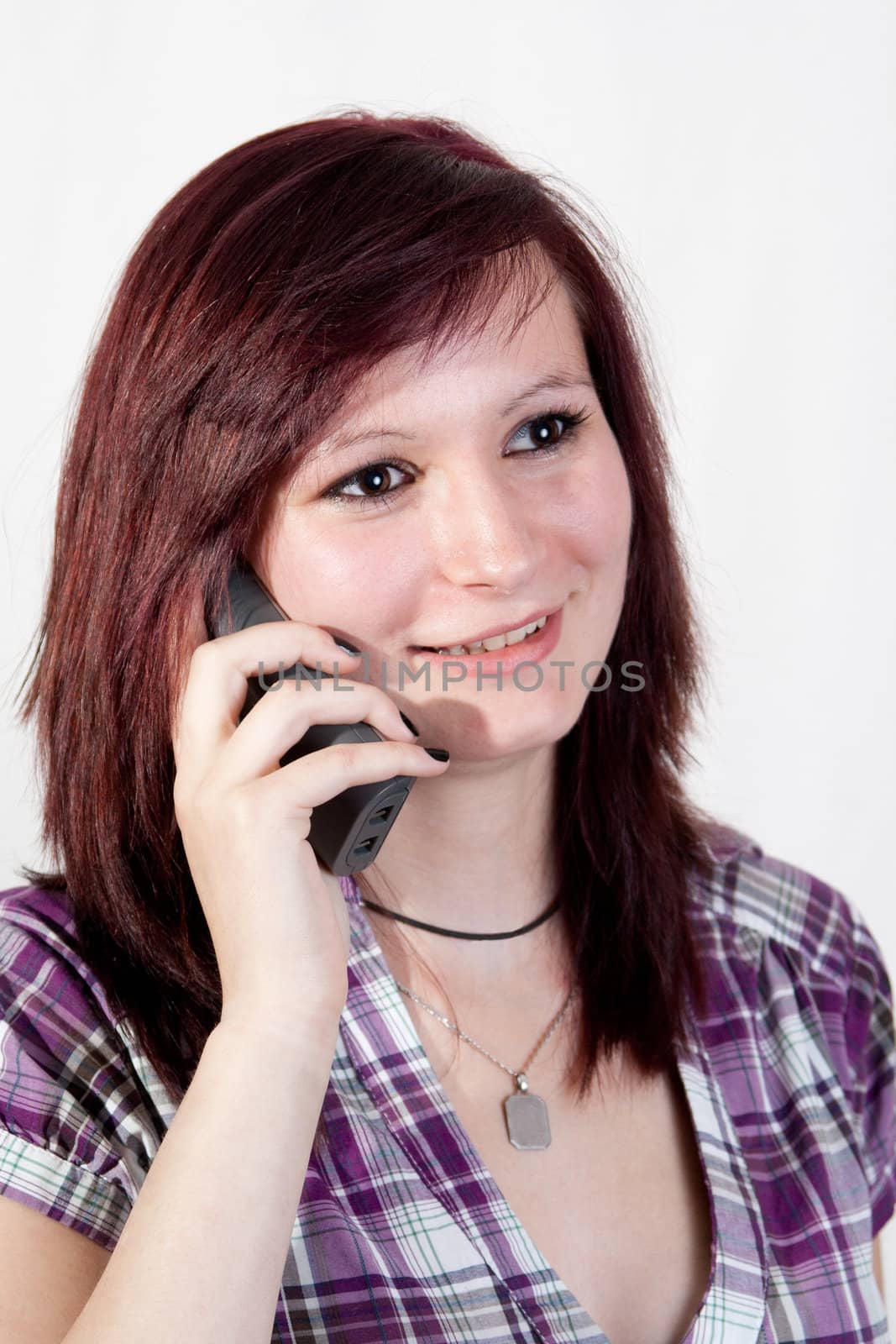 young redhead woman is talking to someone over the smartphone - isolated on white background