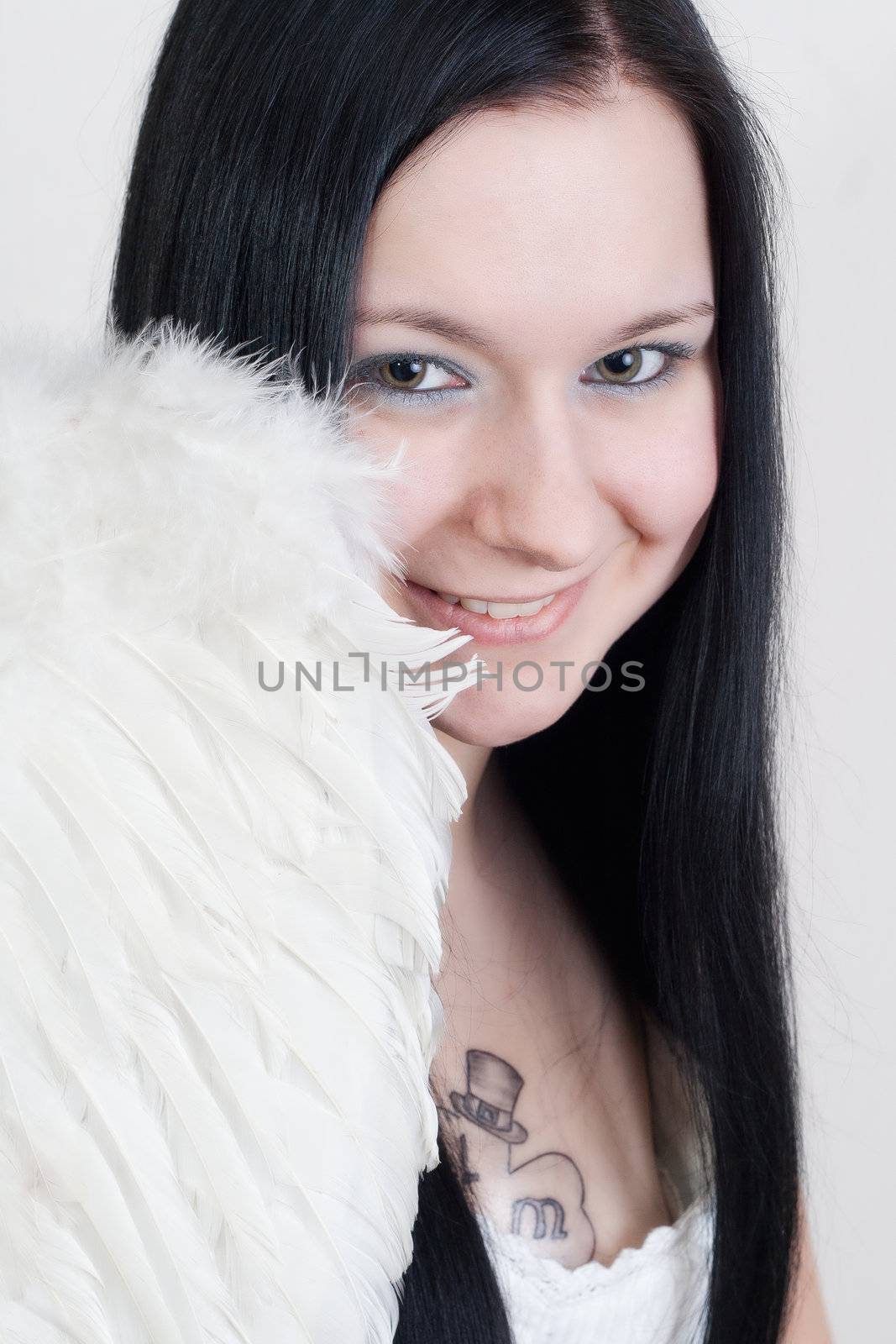 Young blackhaired woman with angel wings smiling -  isolated on white background
