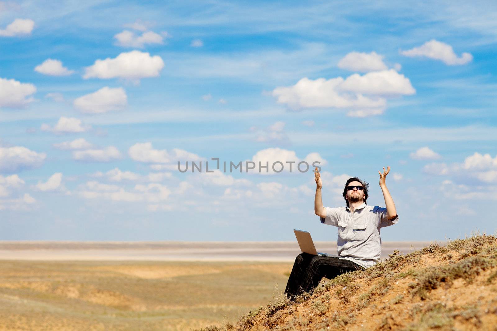 man with laptop praying to the God outdoors