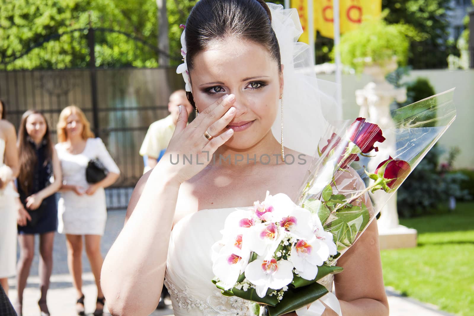Emotional bride holding floral bouquet bridal and wipes the tears