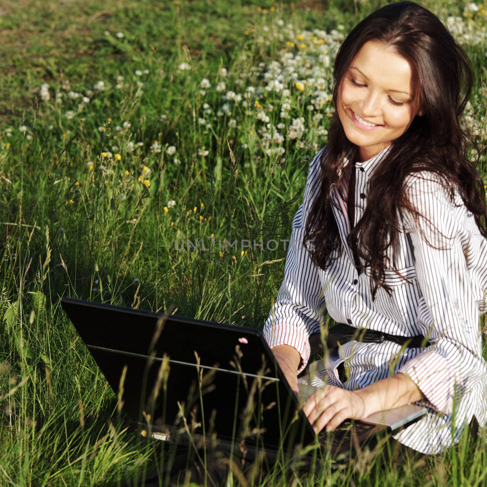 girl with laptop on green grass