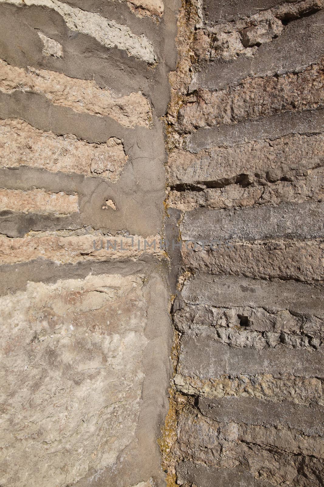 The corner of an old weathered grey brick wall.