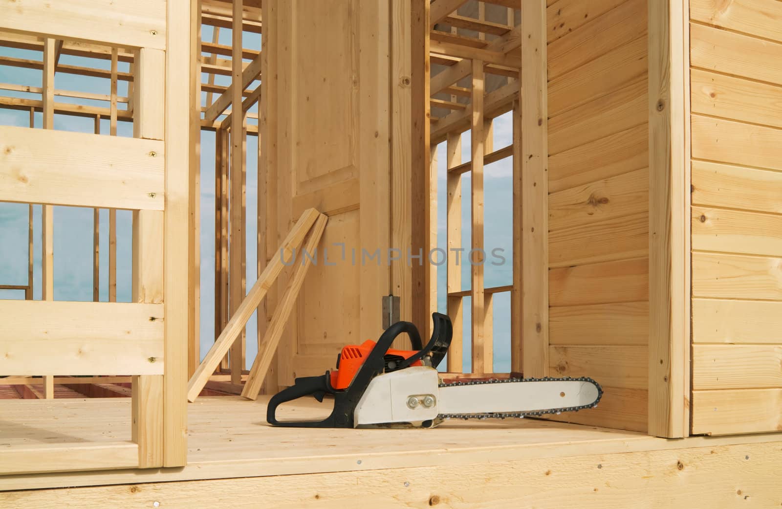 The construction of wood frame house with a chainsaw in the foreground