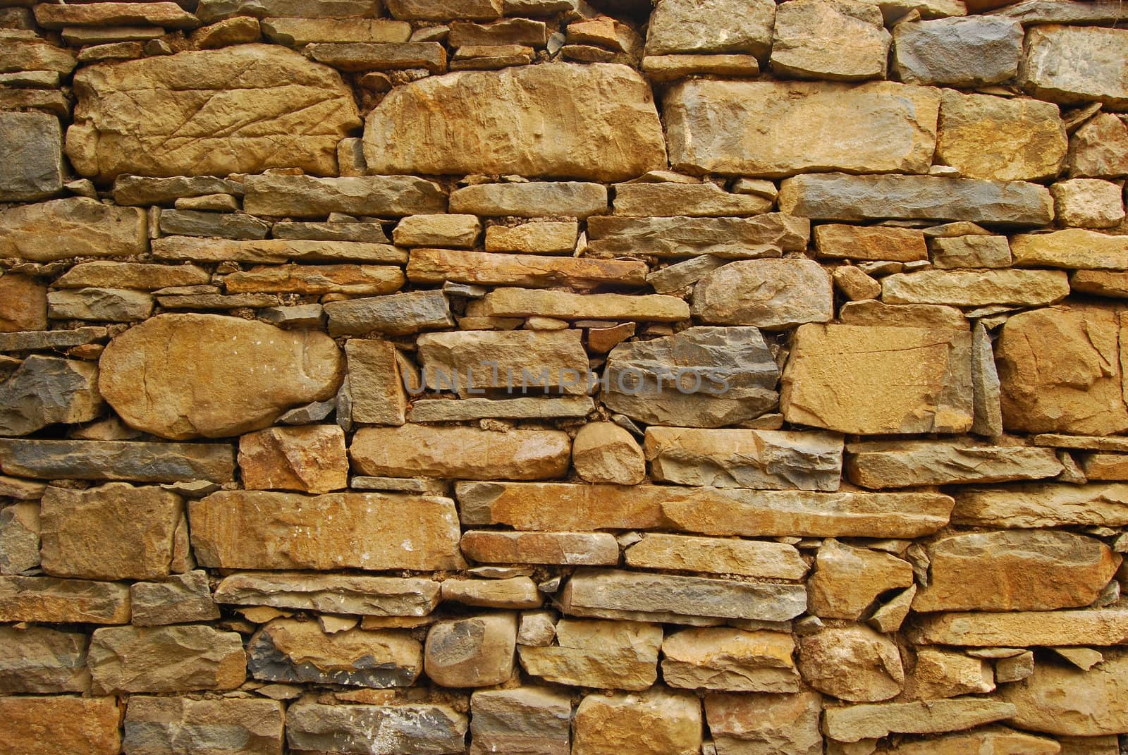 Old dry masonry stonewall, different stones, as background