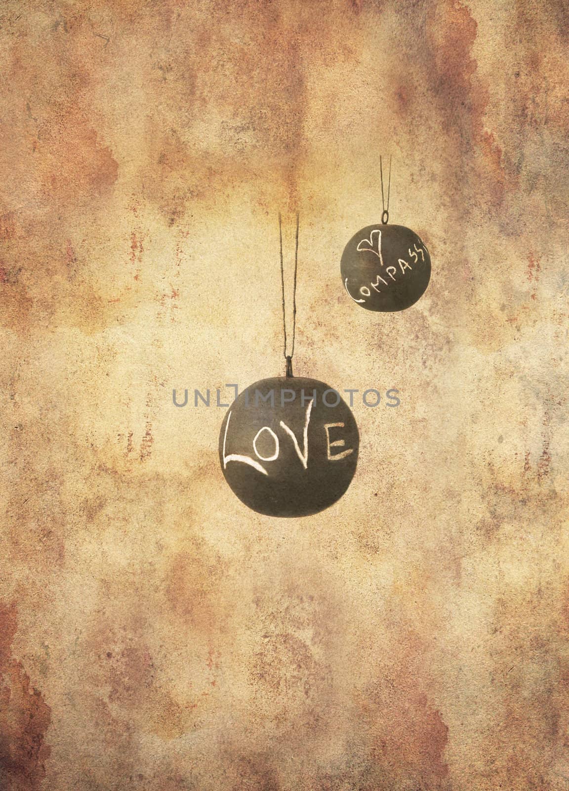 Two slate balls with the message love and compassion written by hand in chalk hanging freely, in grunge style.