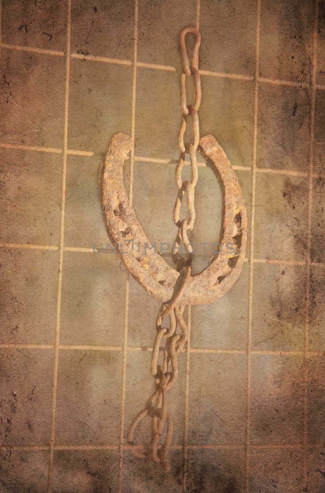 Grungy lucky horse shoe hanging in a chain on a rebar. Rusty and vintage look.