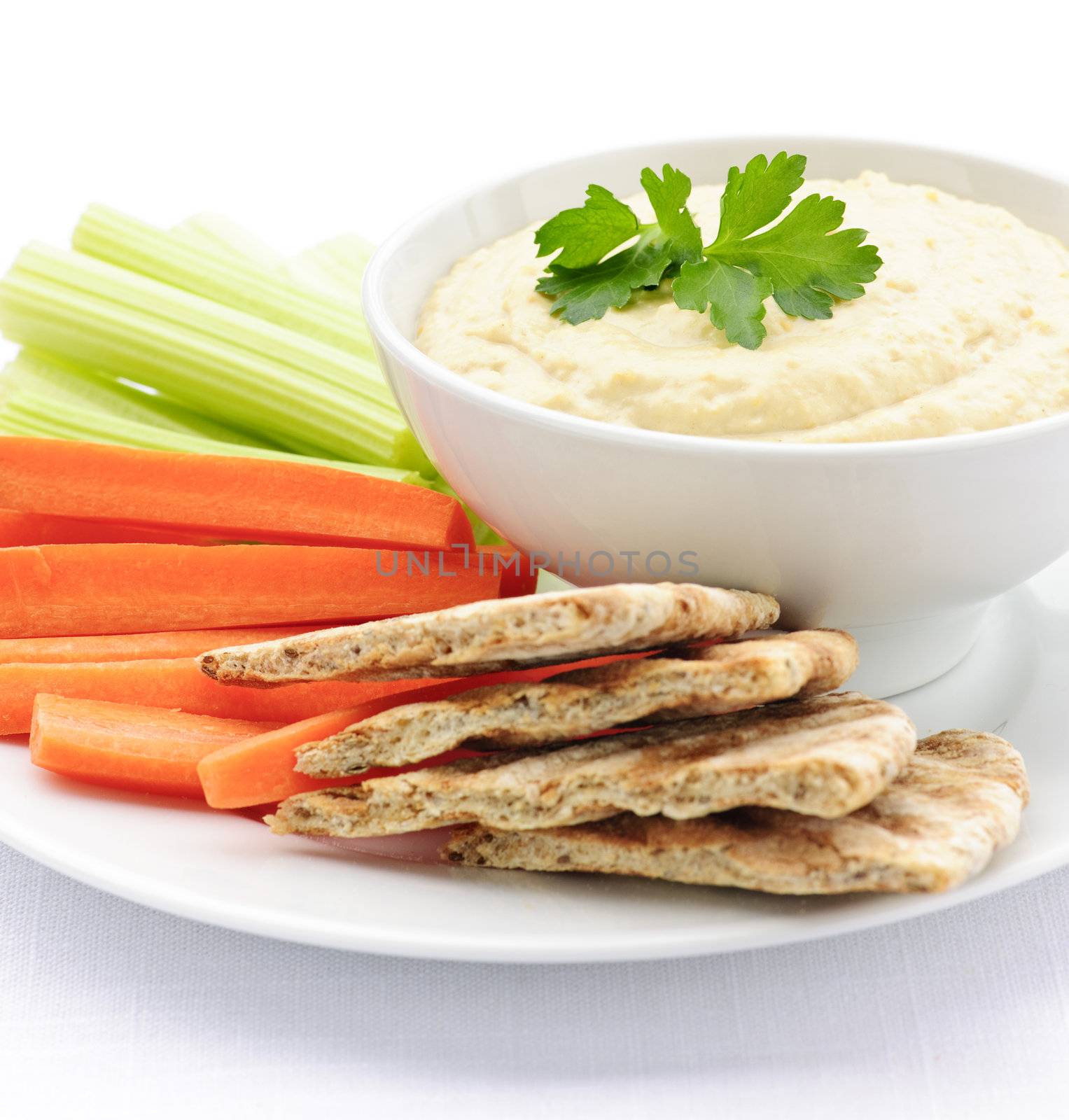 Healthy snack of hummus dip with pita bread slices and vegetables