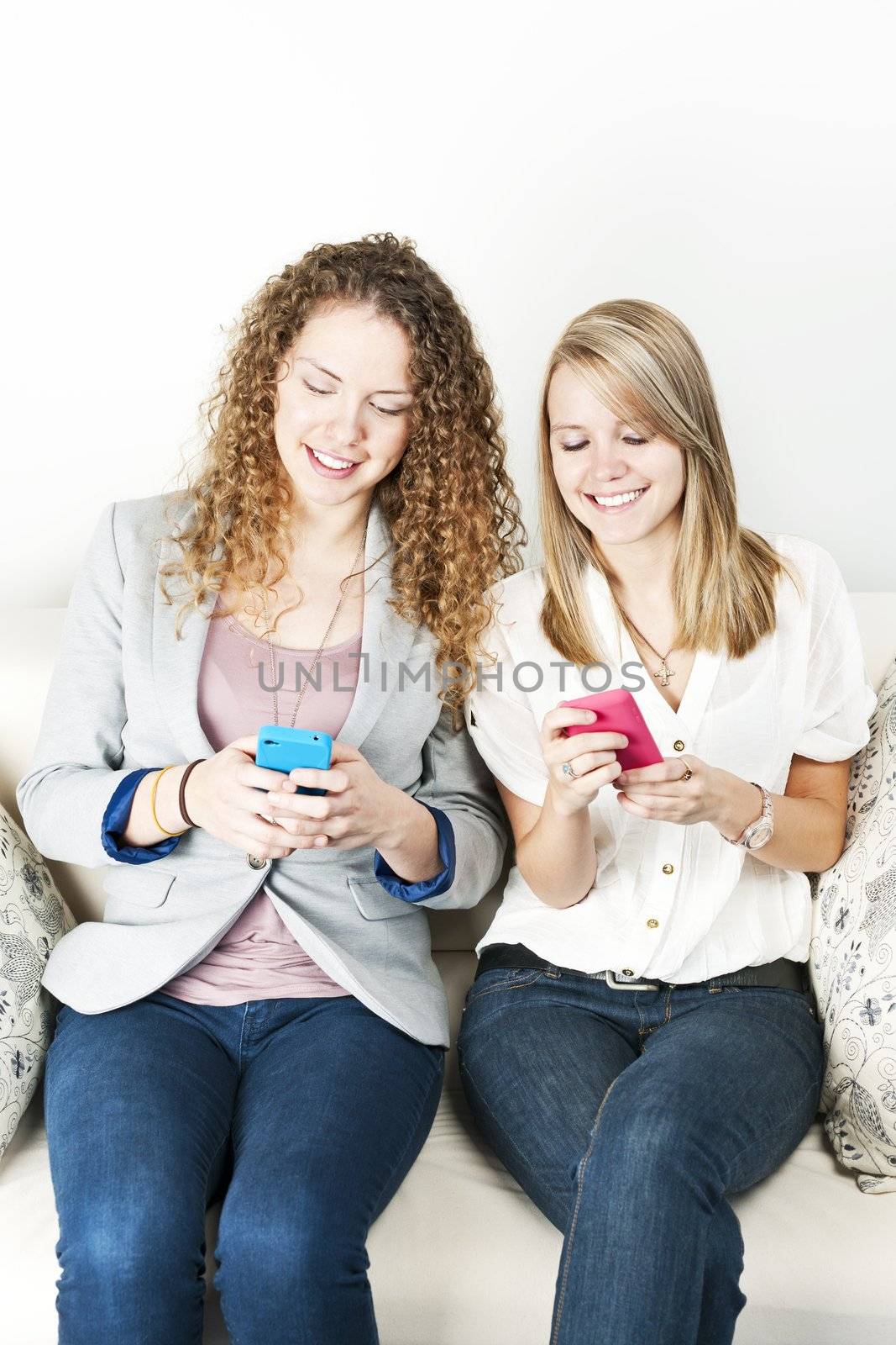 Two women using mobile devices by elenathewise