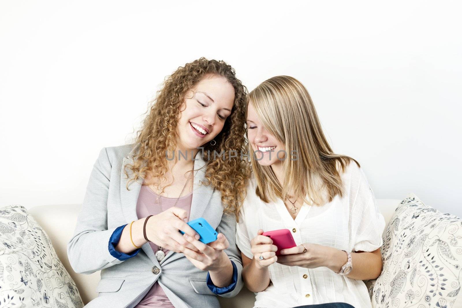 Two women using mobile devices by elenathewise