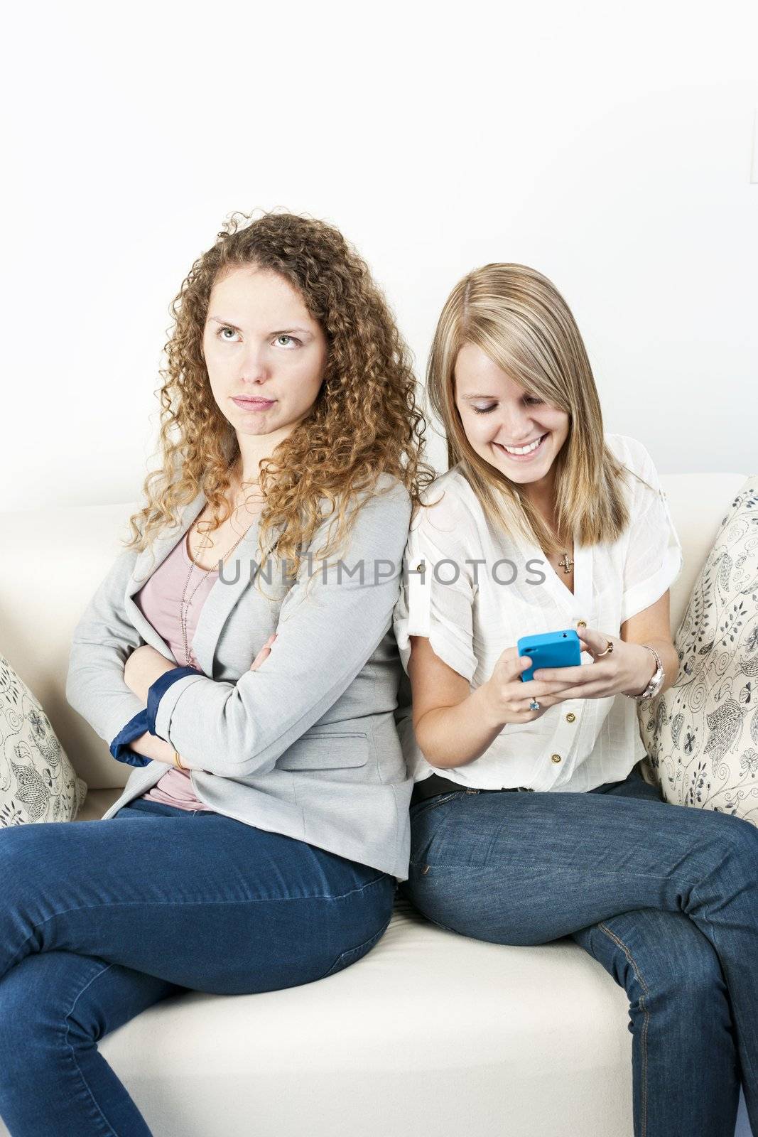 Young woman ignoring her friend checking smart phone breaching cellphone etiquette