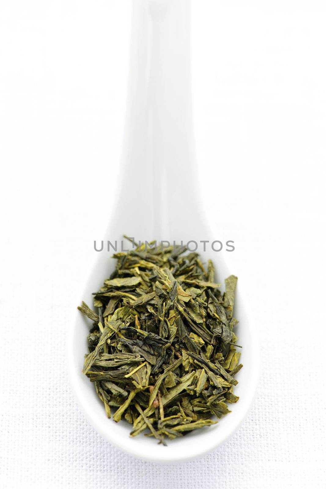 Green dry tea leaves on a spoon