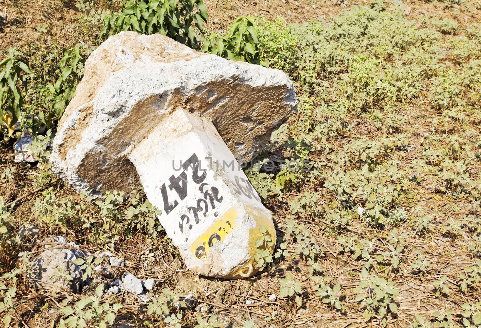 Landscape of a irresponsibly dumped milestone in a field of Gujarat hinterlands by road builders