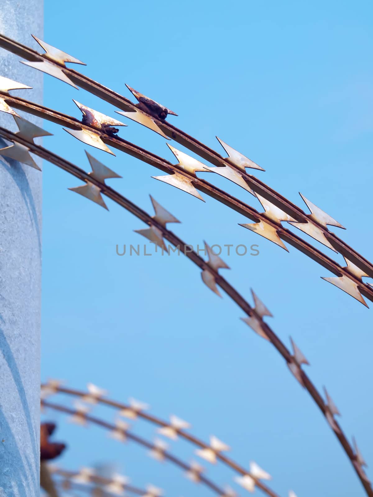 Grunge barbed wire fence against blue sky 