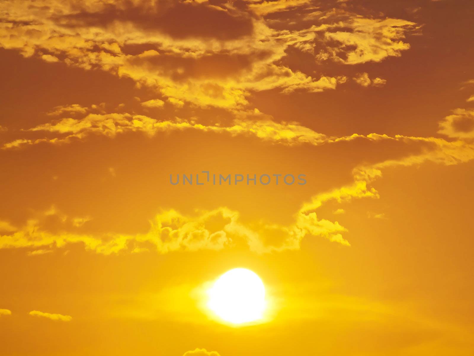 Sun shining through clouds with golden sky