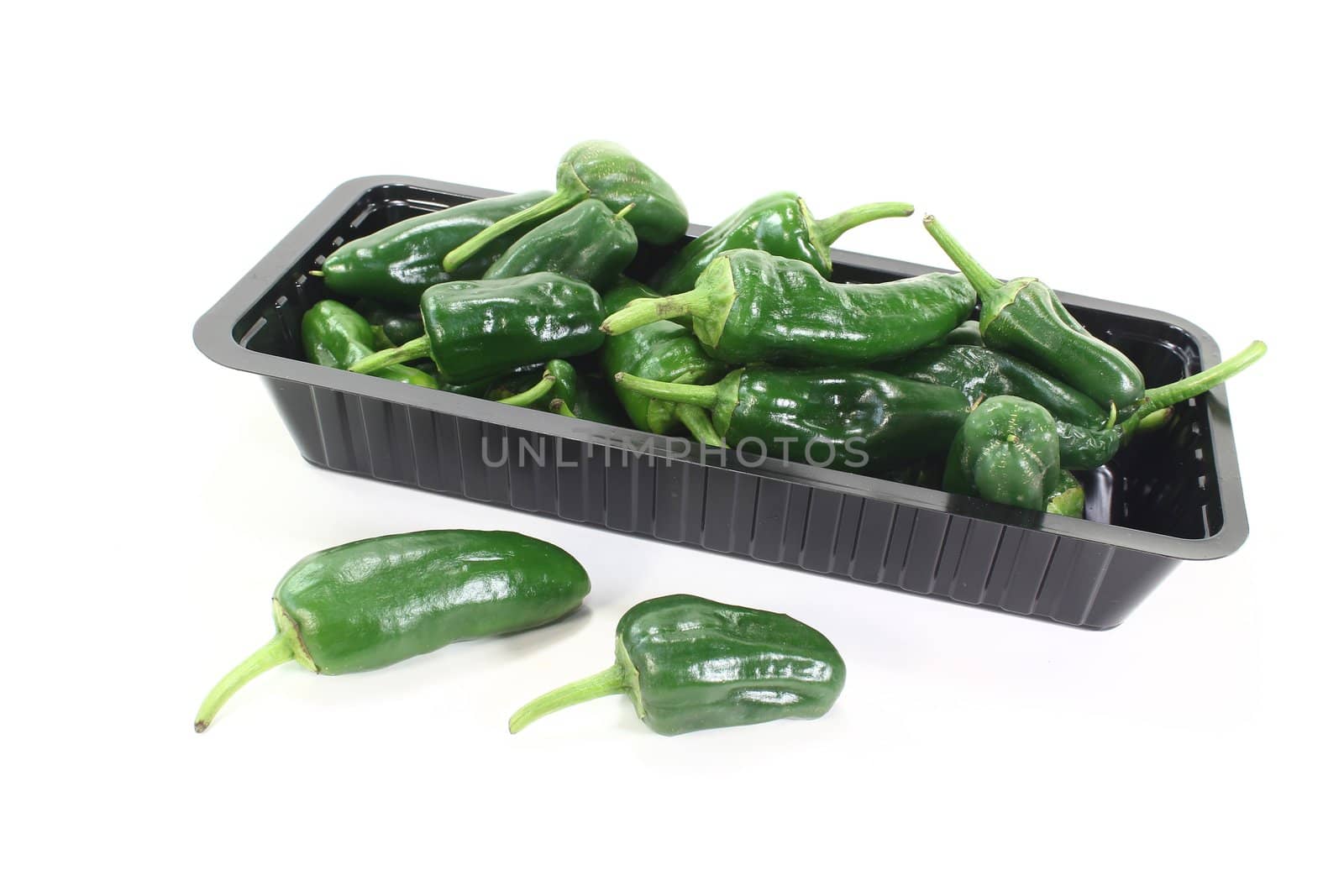 fresh green pimientos in a bowl on light background