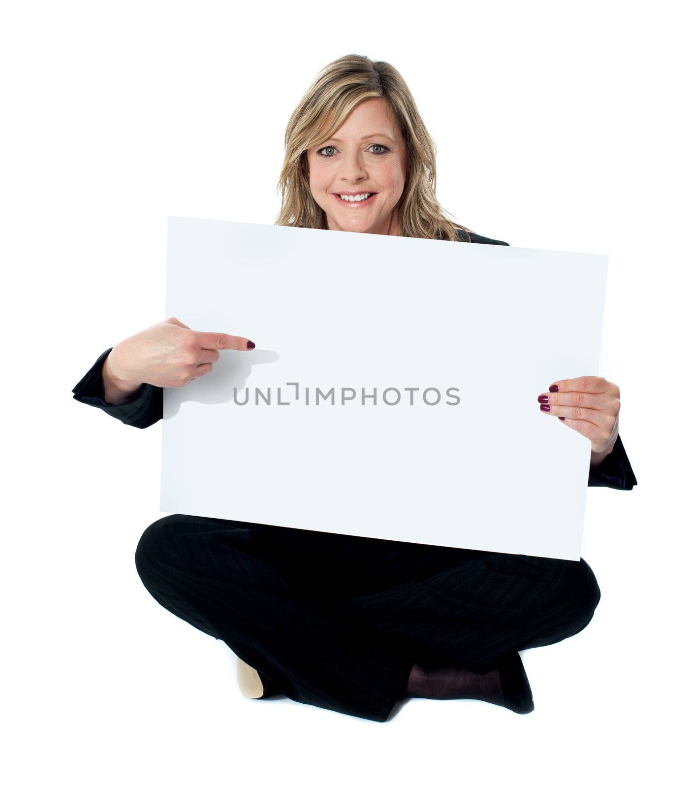 Professional female executive pointing towards billboard seated on floor