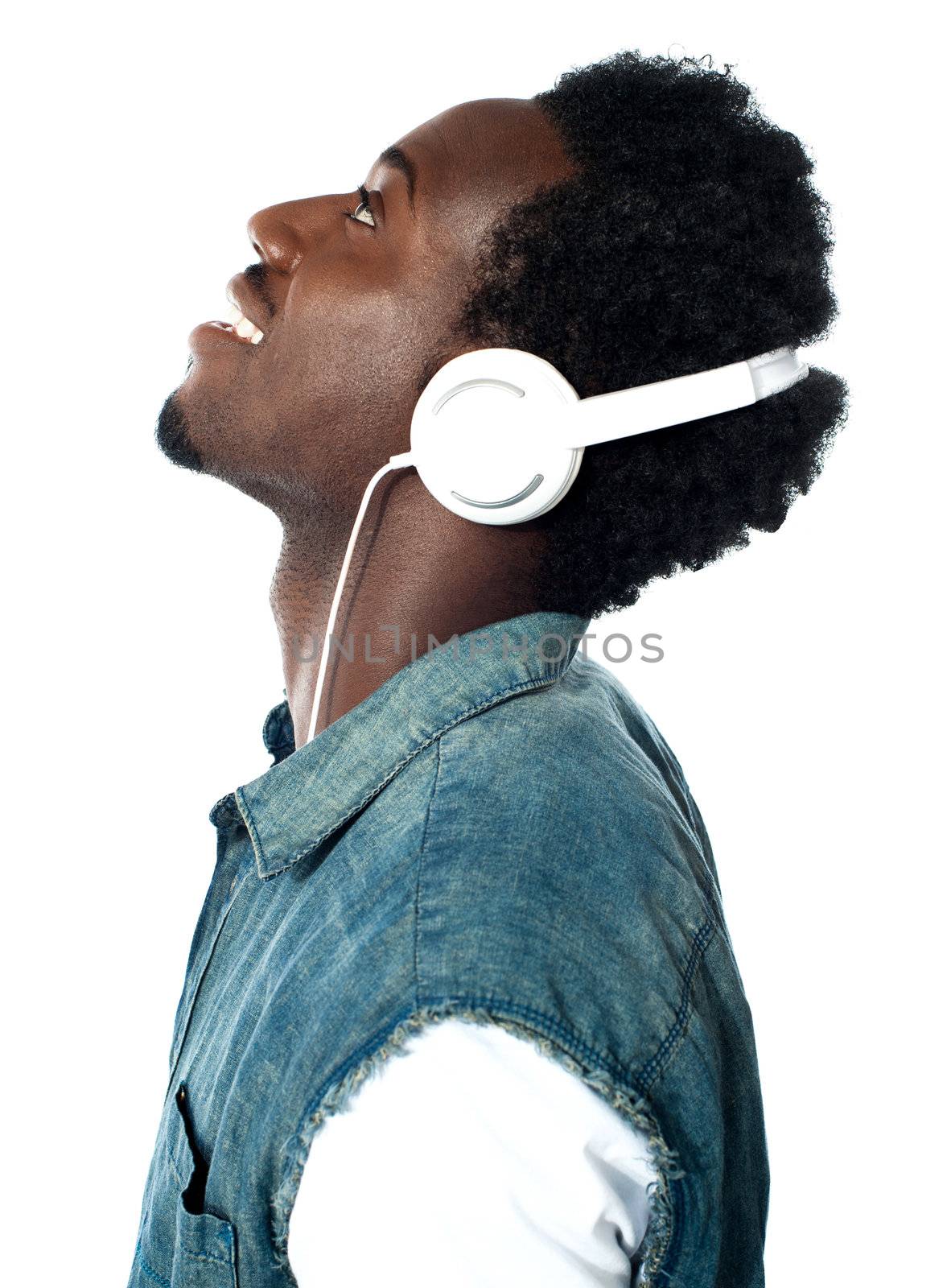 A handsome young boy listening to music on his mp3 player, looking up