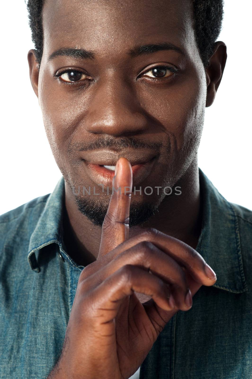 Silence gesture by a young guy against white background. Closeup view